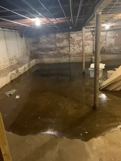 Standing water across an unfinished basement floor during a flood in central New Jersey