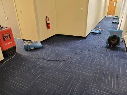 Dehumidifier and air movers on carpet tile in an office hallway downtown