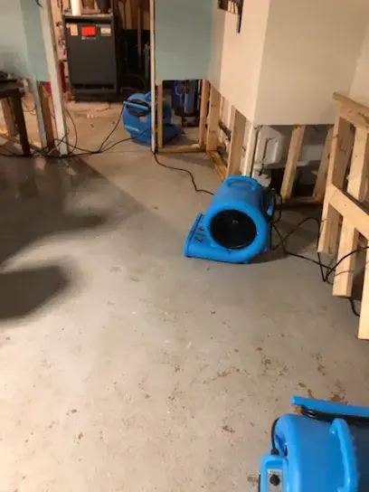 Air mover drying a basement floor with the lower drywall cut away in Monroe Township