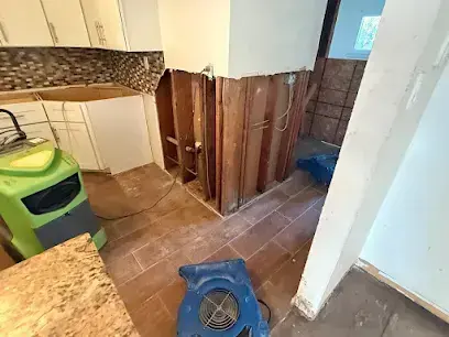 Kitchen cabinets and lower walls opened with air movers drying after an appliance leak in Monroe Township