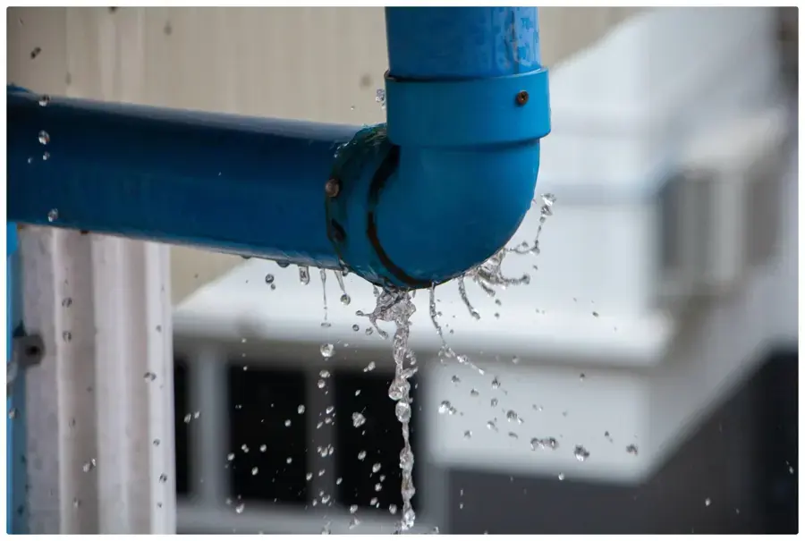 Water spraying and dripping from a leaking pipe elbow in a Monroe Township home