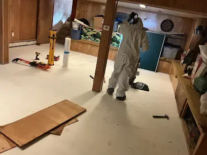 Technician in a protective suit and respirator working in a basement during sewage cleanup in Monroe Township