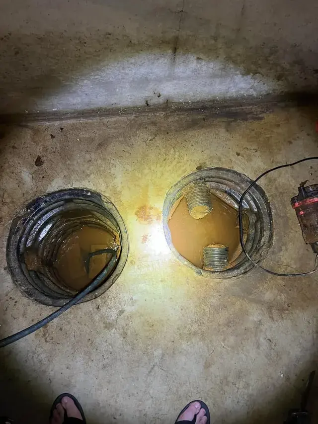 Sump pits in a basement floor holding water after a pump failure in Monroe Township