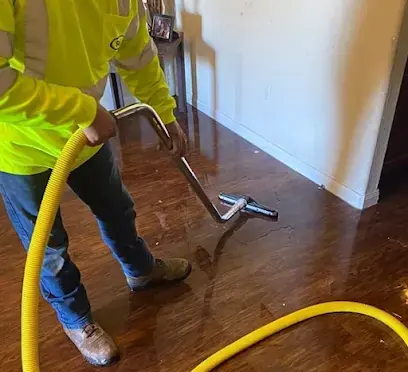 Technician running an extraction wand across a wet wood floor in a Monroe Township home